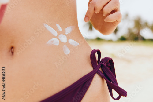Woman in bikini applying sunscreen, with flower painted on her stomach and arm