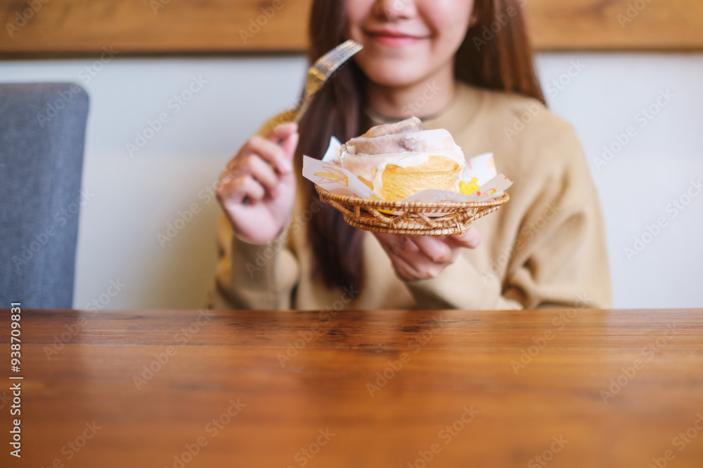 Closeup image of a young woman holding and eating cinnamon roll Closeup image of a young woman holding and eating cinnamon roll