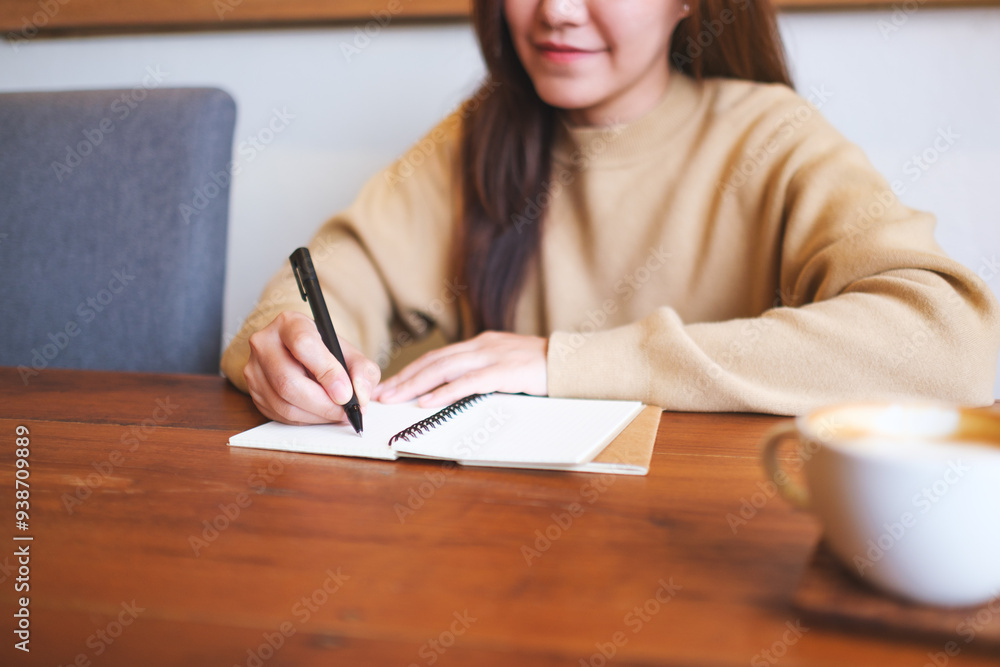 Closeup image of a young woman writing on a notebook on the table Closeup image of a young woman writing on a notebook on the table
