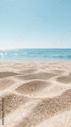 A serene beach scene with soft, sunlit sand and gentle waves under a bright, clear blue sky, evoking a sense of tranquility.