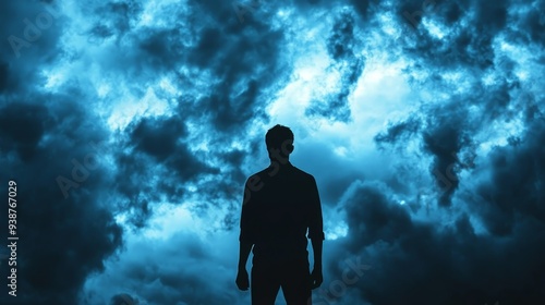 A lone man stands in silhouette against a backdrop of swirling, stormy clouds. The image evokes a sense of mystery, solitude, and the vastness of nature.