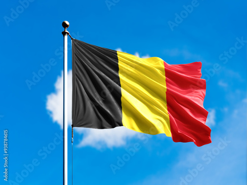 Belgium flag flying on blur blue clouds background.