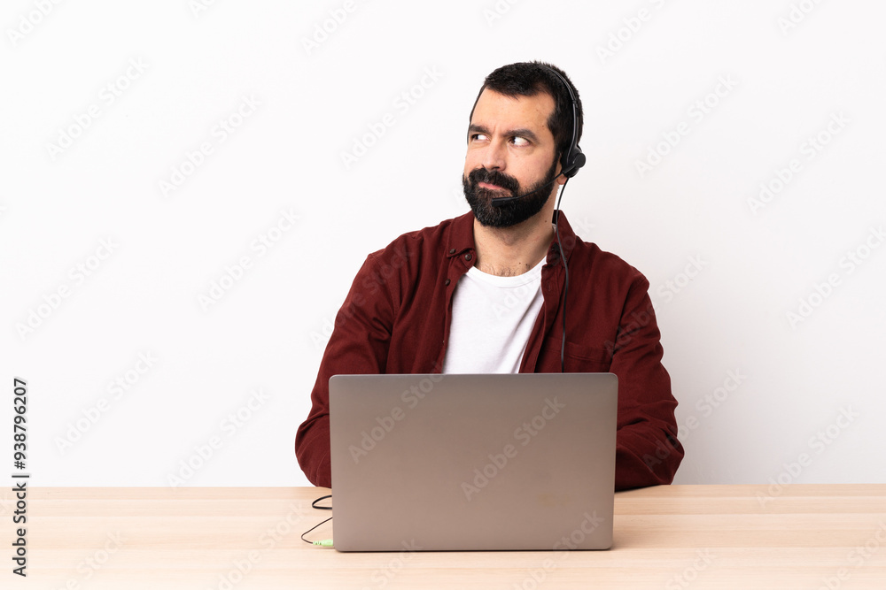 Telemarketer caucasian man working with a headset and with laptop having doubts while looking side. Telemarketer caucasian man working with a headset and with laptop having doubts while looking side.