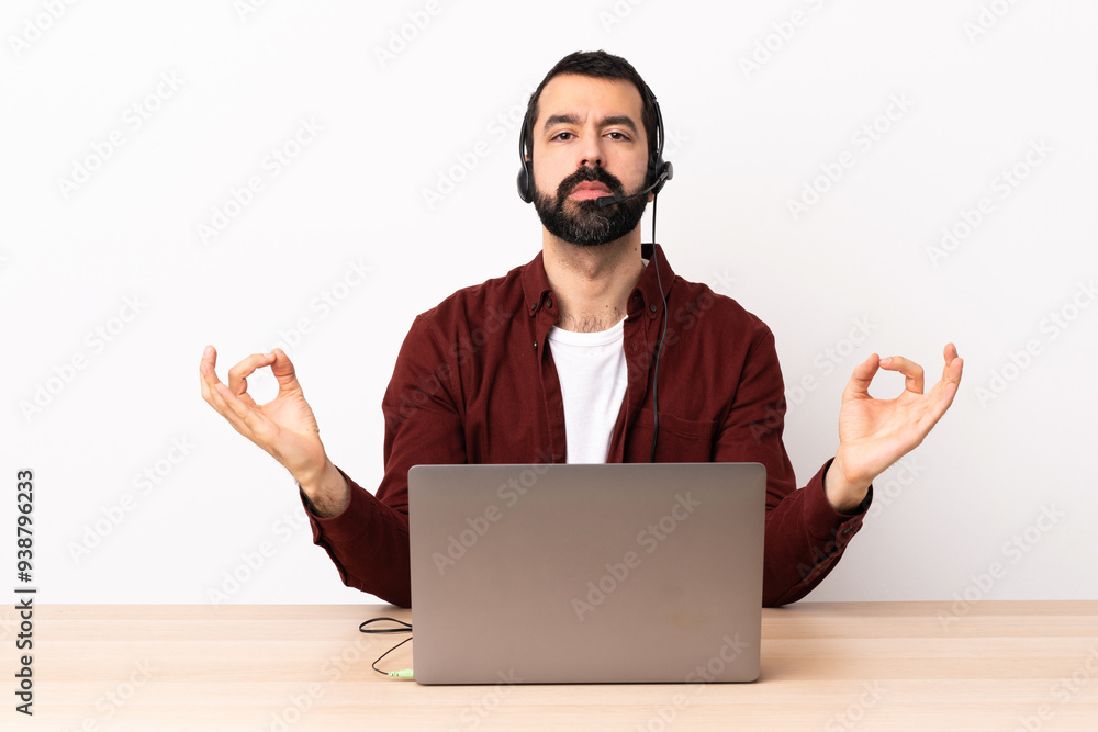 Telemarketer caucasian man working with a headset and with laptop in zen pose. Telemarketer caucasian man working with a headset and with laptop in zen pose.