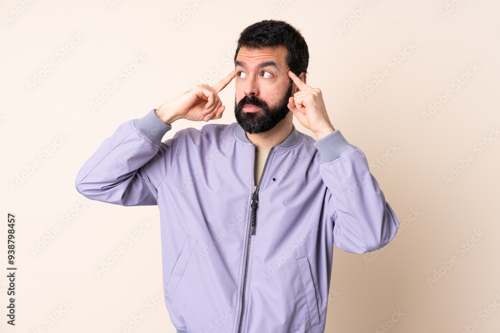 Caucasian man with beard wearing a jacket over isolated background having doubts and thinking Caucasian man with beard wearing a jacket over isolated background having doubts and thinking
