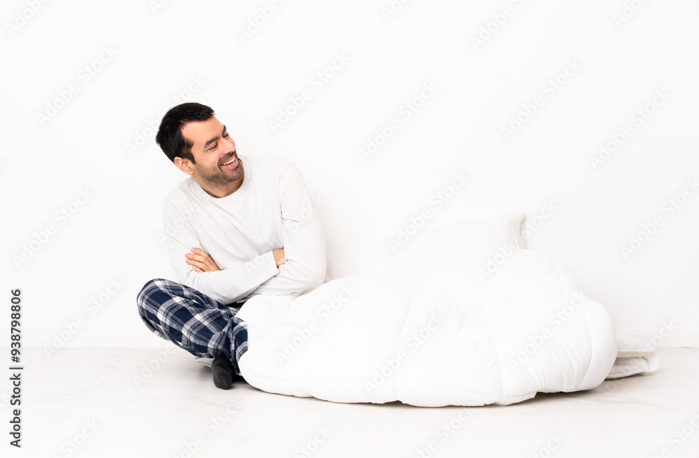 Caucasian man in pajamas sitting on the floor at indoors with arms crossed and happy Caucasian man in pajamas sitting on the floor at indoors with arms crossed and happy