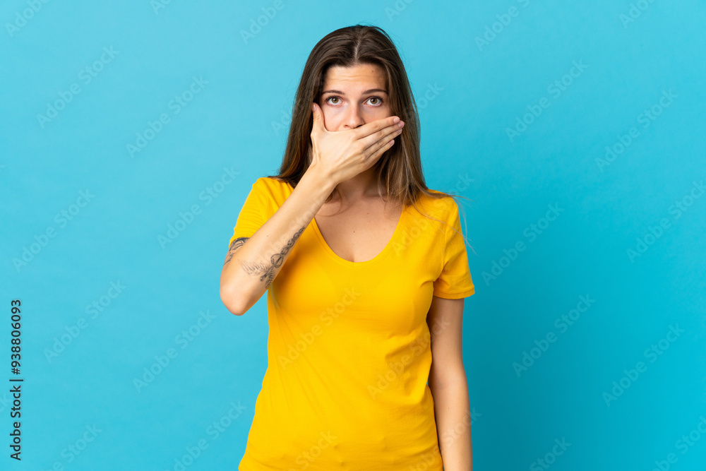 Young slovak woman isolated on blue background covering mouth with hand Young slovak woman isolated on blue background covering mouth with hand