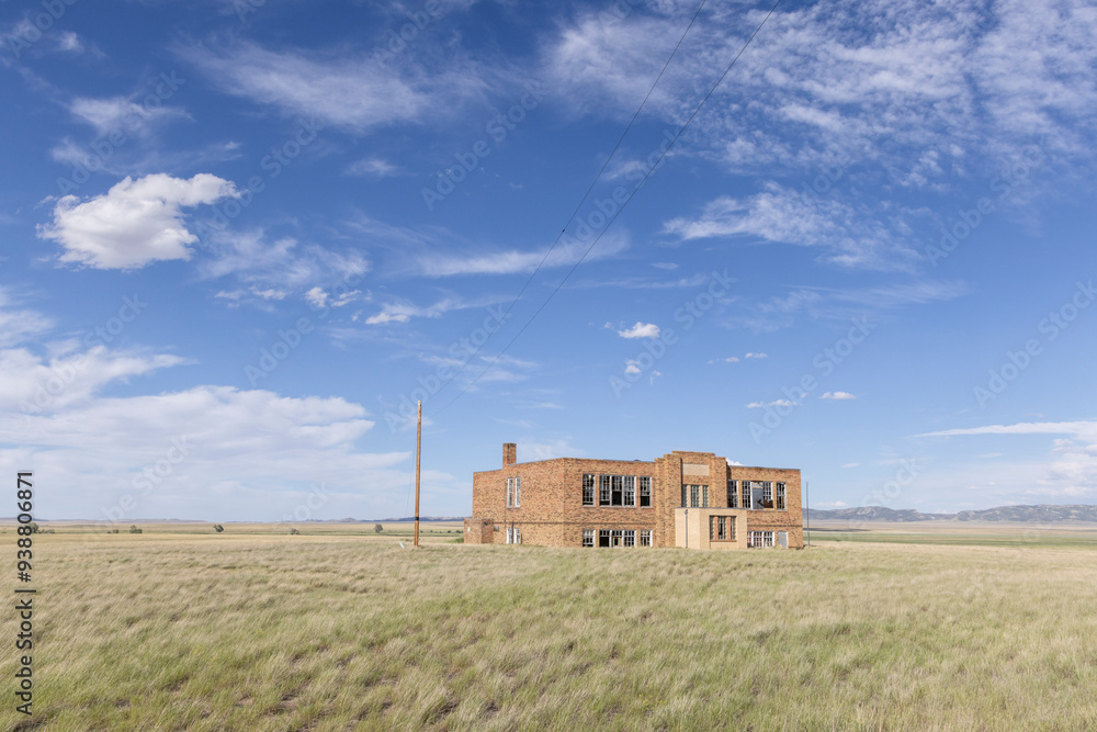An abandoned school building standing in a field