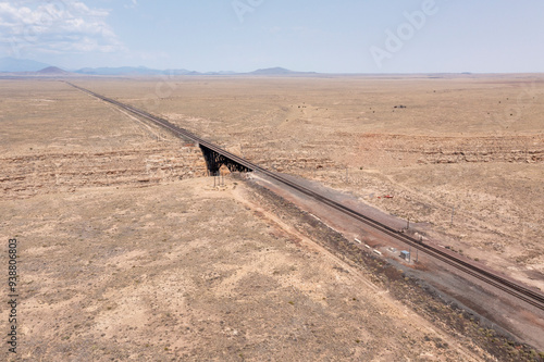 Vacant train tracks going over a bridge and into the desert horizon photo