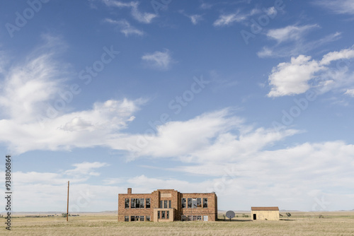 An abandoned school building standing in a field wide view photo