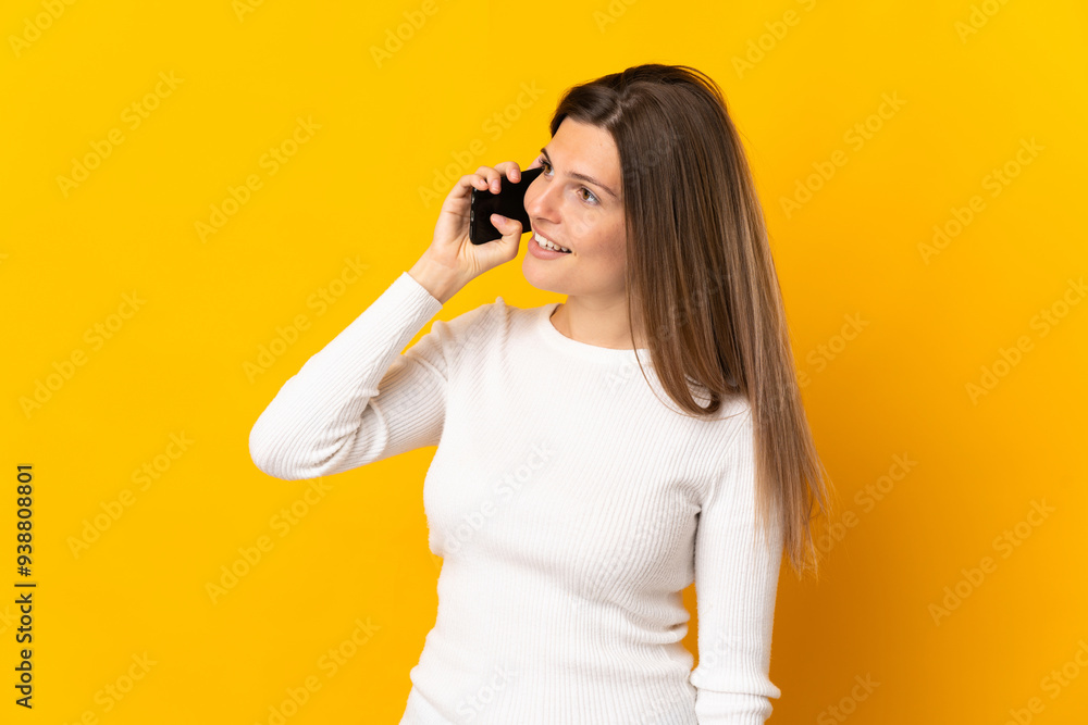 Young Slovak woman isolated on yellow background keeping a conversation with the mobile phone Young Slovak woman isolated on yellow background keeping a conversation with the mobile phone