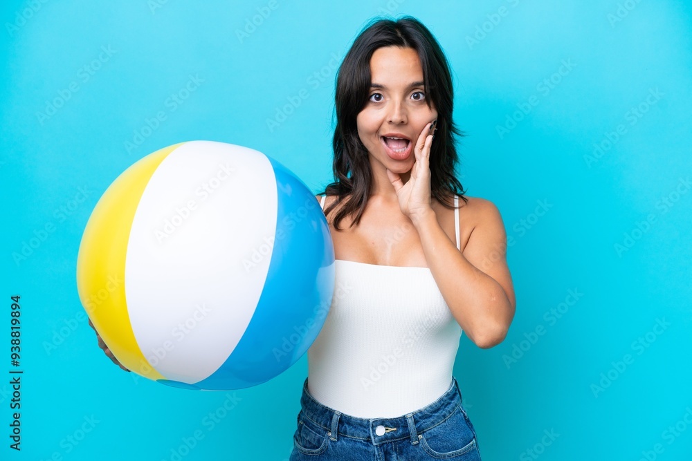 Young hispanic woman holding beach ball isolated on blue background with surprise and shocked facial expression Young hispanic woman holding beach ball isolated on blue background with surprise and shocked facial expression