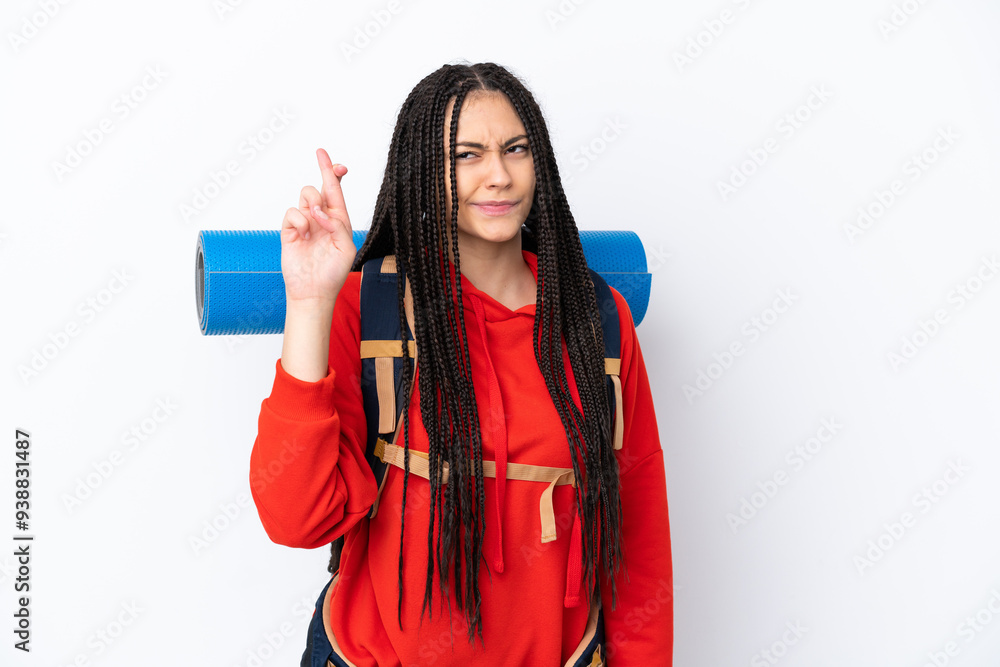 Hiker teenager girl with braids over isolated white background with fingers crossing and wishing the best Hiker teenager girl with braids over isolated white background with fingers crossing and wishing the best