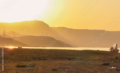 Sunset at Al Ain Al Sokhna, Suez, Egypt, with a truck driving along the beach. Mountains and soft sunlight create a tranquil backdrop