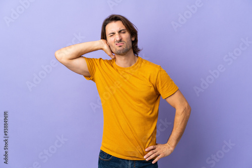 Young handsome man isolated on purple background with neckache photo