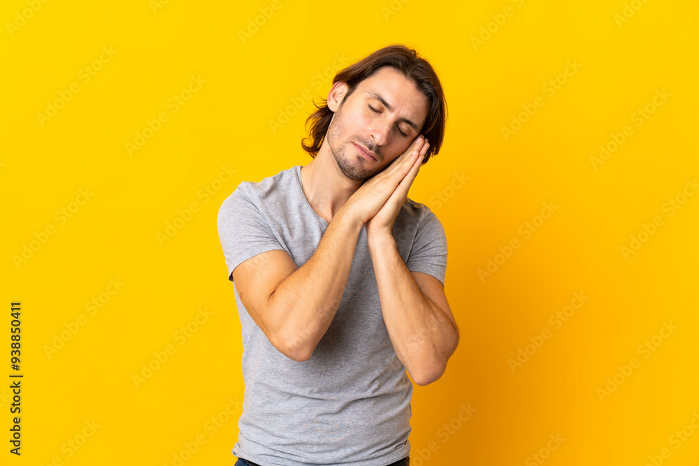 Young handsome man isolated on yellow background making sleep gesture in dorable expression Young handsome man isolated on yellow background making sleep gesture in dorable expression