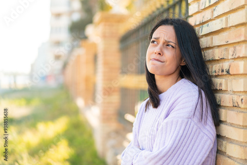Young woman at outdoors with confuse face expression
