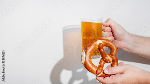 Hands holding a traditional pretzel and beer mug celebrating Oktoberfest, showcasing German cultural festivities photo