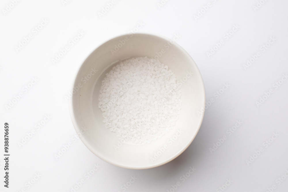 A white ceramic bowl filled with sea salt on a plain background, emphasizing simplicity and minimalism in cooking A white ceramic bowl filled with sea salt on a plain background, emphasizing simplicity and minimalism in cooking