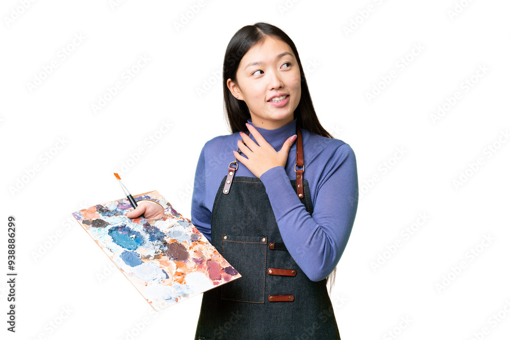 Young artist woman holding a palette over isolated chroma key background looking up while smiling Young artist woman holding a palette over isolated chroma key background looking up while smiling