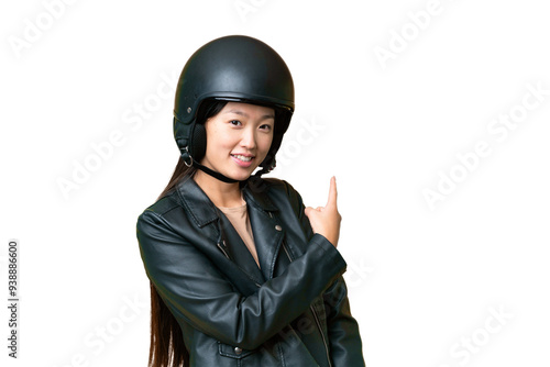 Young Asian woman with a motorcycle helmet over isolated chroma key background pointing back