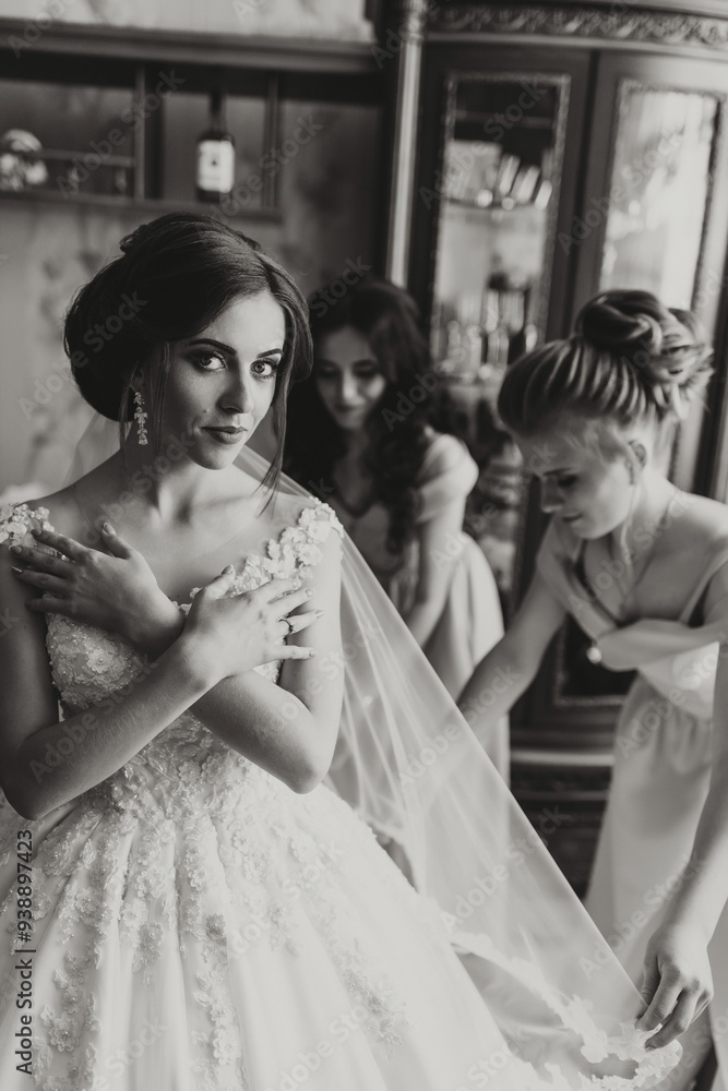Fototapeta premium A woman in a wedding dress is getting ready with two other women. Scene is one of celebration and camaraderie