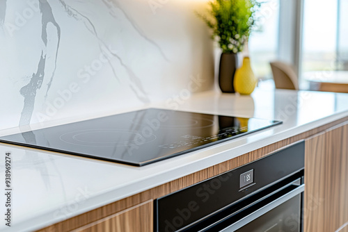 Close up of ceramic electric stove top on white marble countertop in a modern kitchen with wooden cabinets, front view. photo