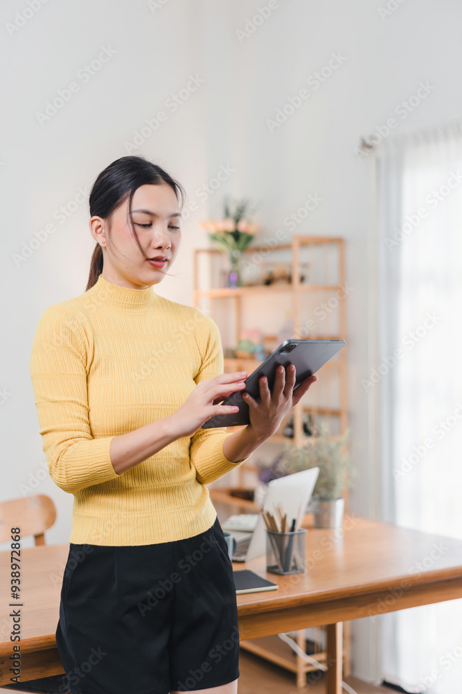 Asian woman working on digital tablet at desk. Asian woman working on digital tablet at desk.