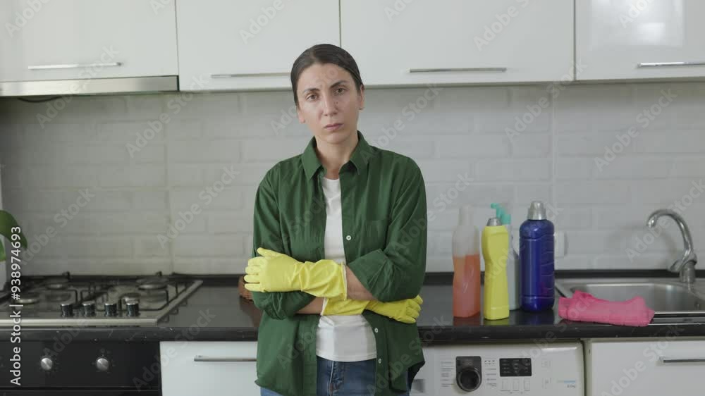 Exhausted Housewife with Crossed Hands in Kitchen, Wearing Yellow Gloves