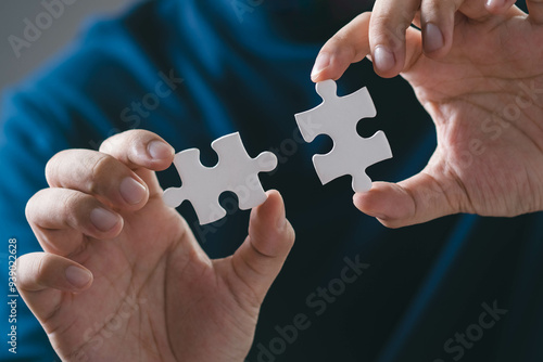 Fotografie Close-up of hands holding two puzzle pieces, symbolizing connection, problem-solving, and collaboration