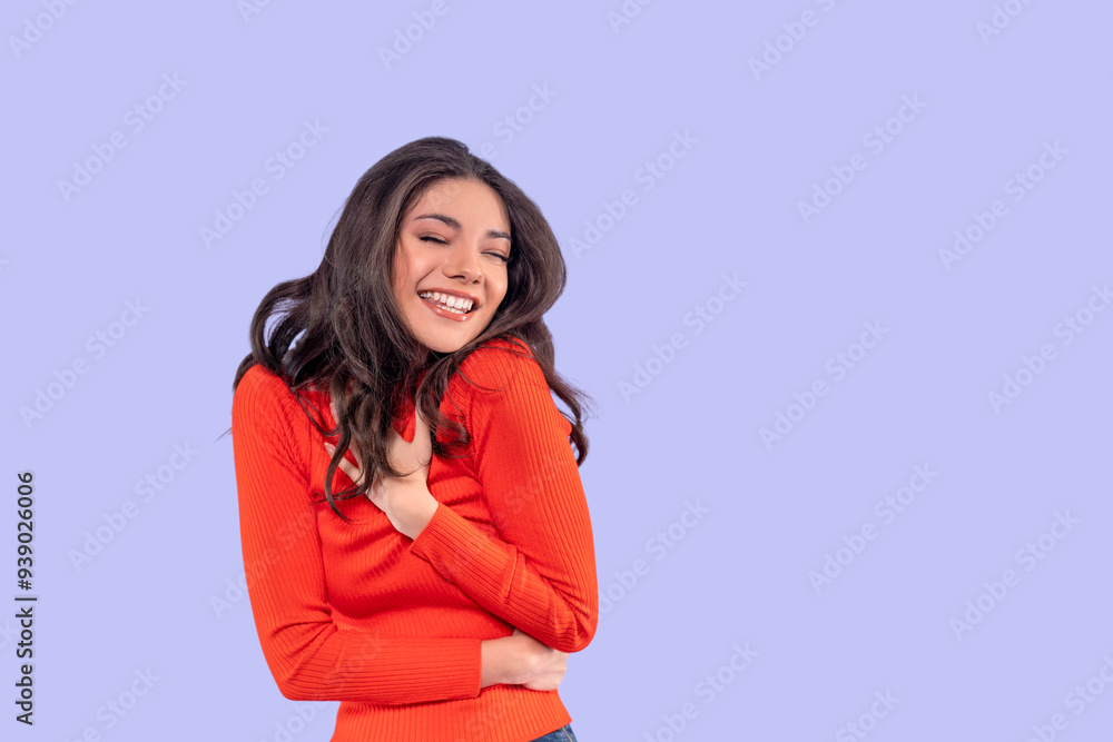 Obraz premium Young Woman in Bright Orange Sweater Expresses Joy Against Pastel Purple Background