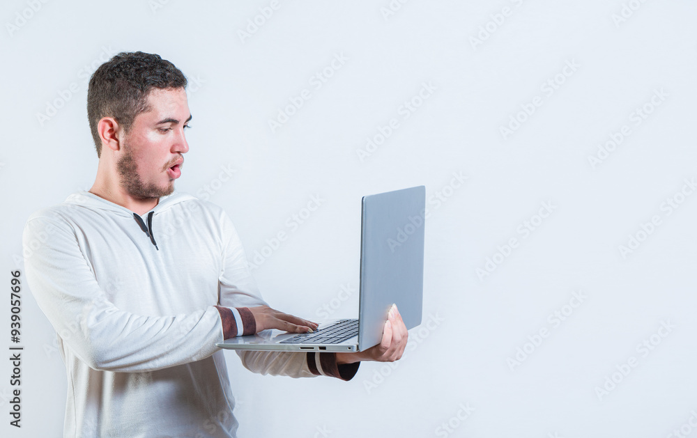 Surprised guy holding and looking at an promotion on laptop screen. Amazed handsome man standing using laptop isolated Surprised guy holding and looking at an promotion on laptop screen. Amazed handsome man standing using laptop isolated