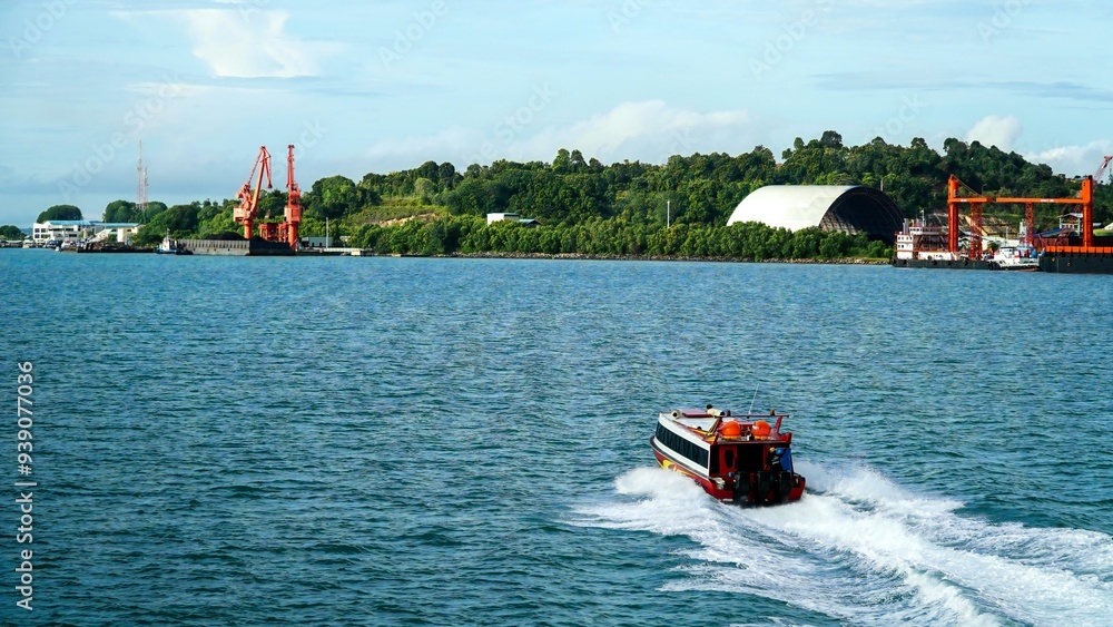 Fototapeta premium photo of a small fast ferry sailing towards the destination port, photo taken from behind