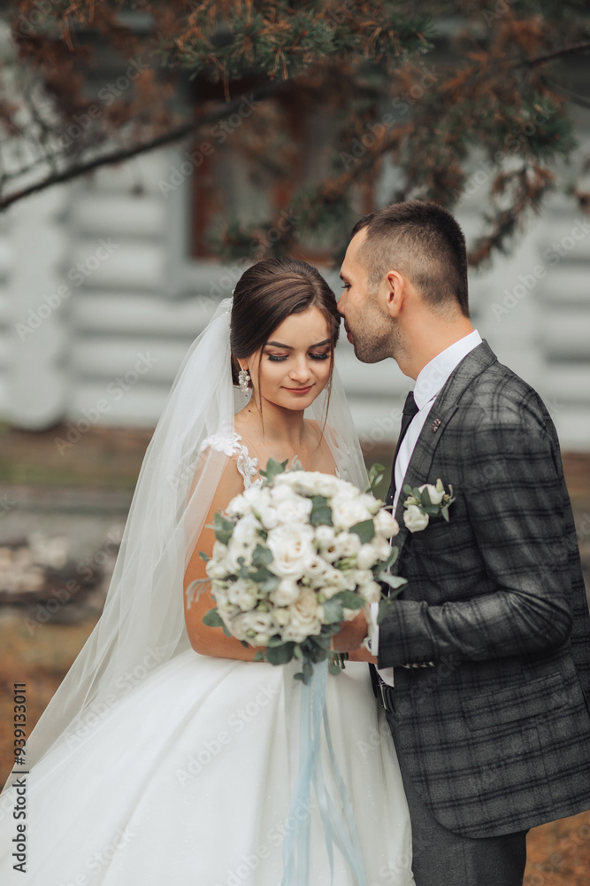 A bride and groom are kissing each other's cheeks while holding a bouquet and a vase A bride and groom are kissing each other's cheeks while holding a bouquet and a vase