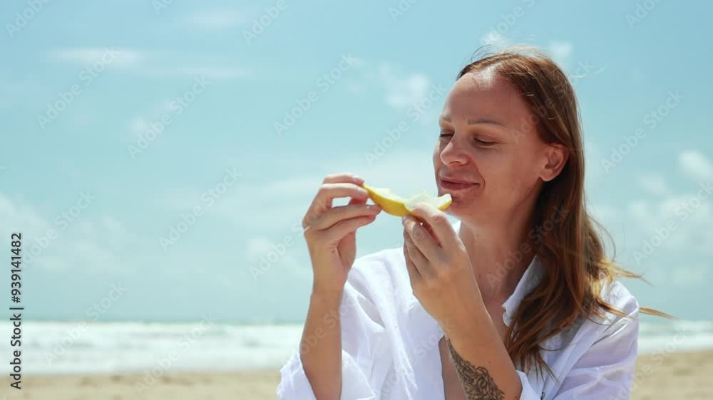 Happy young woman in white shirt and denim shorts, joyfully enjoy slice of melon on sun beach. Slow motion highlights her delight Happy young woman in white shirt and denim shorts, joyfully enjoy slice of melon on sun beach. Slow motion highlights her delight