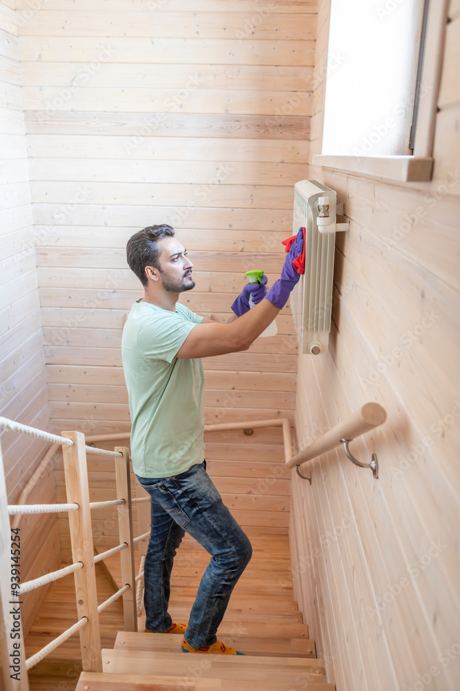 Cheerful man cleans radiator and prepares for harsh winter and heating season Cheerful man cleans radiator and prepares for harsh winter and heating season