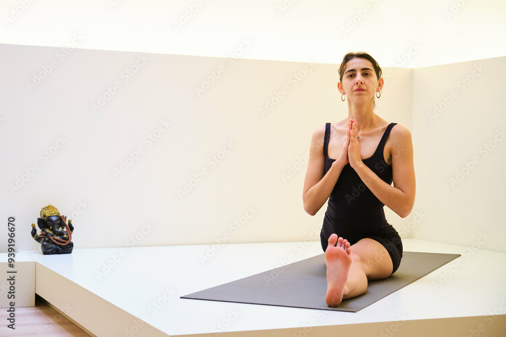 A woman is doing Hanumanasana or monkey yoga pose on a mat. She is in a split position and she is focused on her breathing. A woman is doing Hanumanasana or monkey yoga pose on a mat. She is in a split position and she is focused on her breathing.