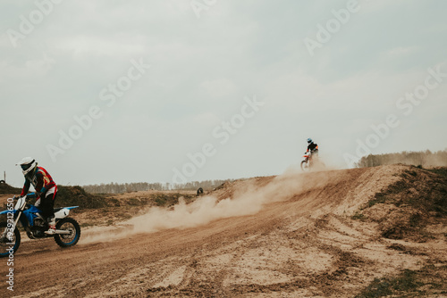 Motorcyclist jumping and riding on rear wheel at enduro motocross training ground