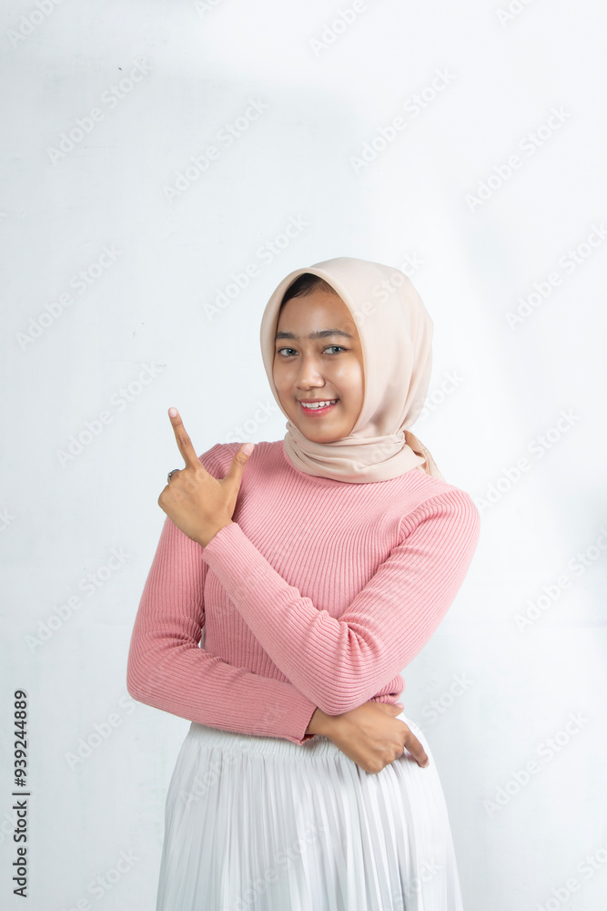 Advertisement The Muslim teenager pointed to the side as if the product next to her had a white background, the woman was wearing a hijab and a pink woven dress and white skirt. Advertisement The Muslim teenager pointed to the side as if the product next to her had a white background, the woman was wearing a hijab and a pink woven dress and white skirt.