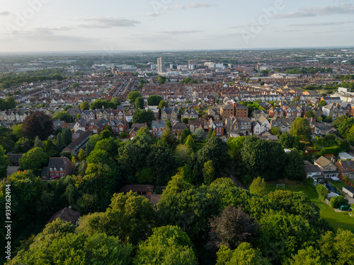 Swindon city center at sunset in the summer. Aerial from Town Gardens towards main train station. Panorama above green tree canopy.