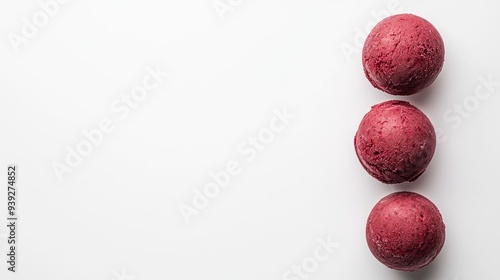 Tiga bola es krim berwarna merah muda di atas latar belakang putih.