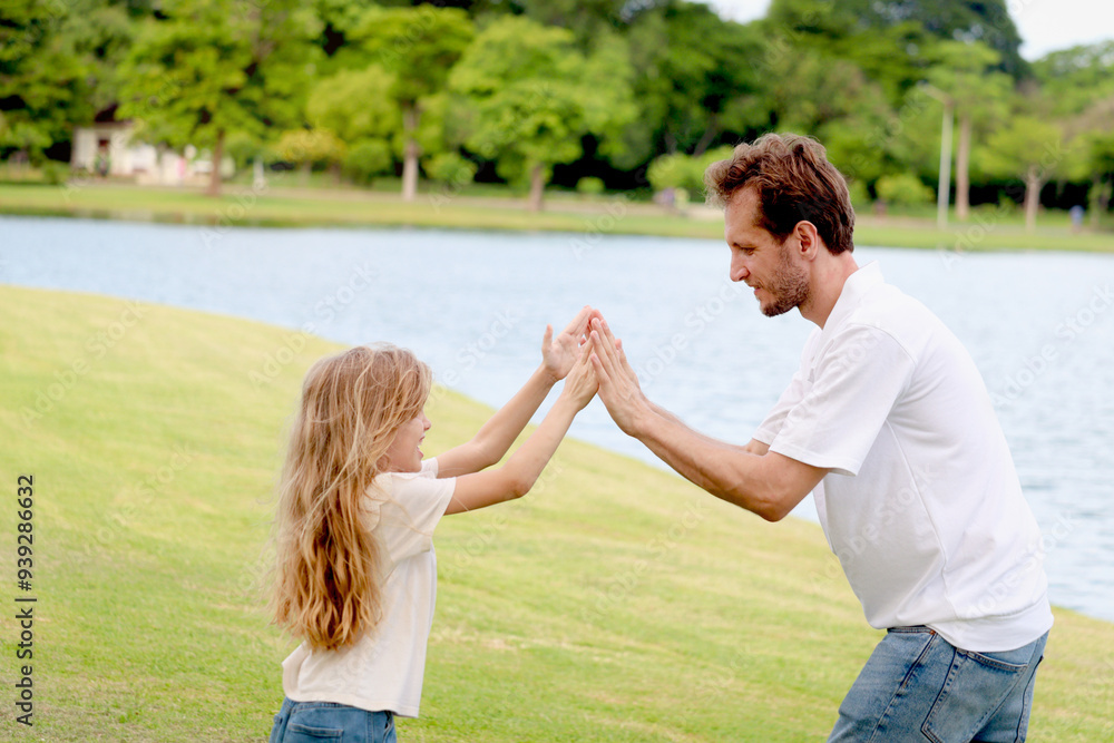 Happy family, father and little daughter girl playing patty cake at beautiful green garden. Joyful parent and kid playing fun outdoor at public park. Cute family spending time outside together. Happy family, father and little daughter girl playing patty cake at beautiful green garden. Joyful parent and kid playing fun outdoor at public park. Cute family spending time outside together.