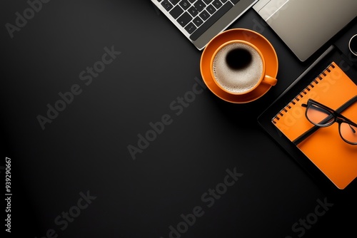 A minimalistic overhead shot showing an orange coffee cup, a pair of glasses, a notebook, and a laptop on a clean, matte black desk surface, symbolizing productivity and organization.