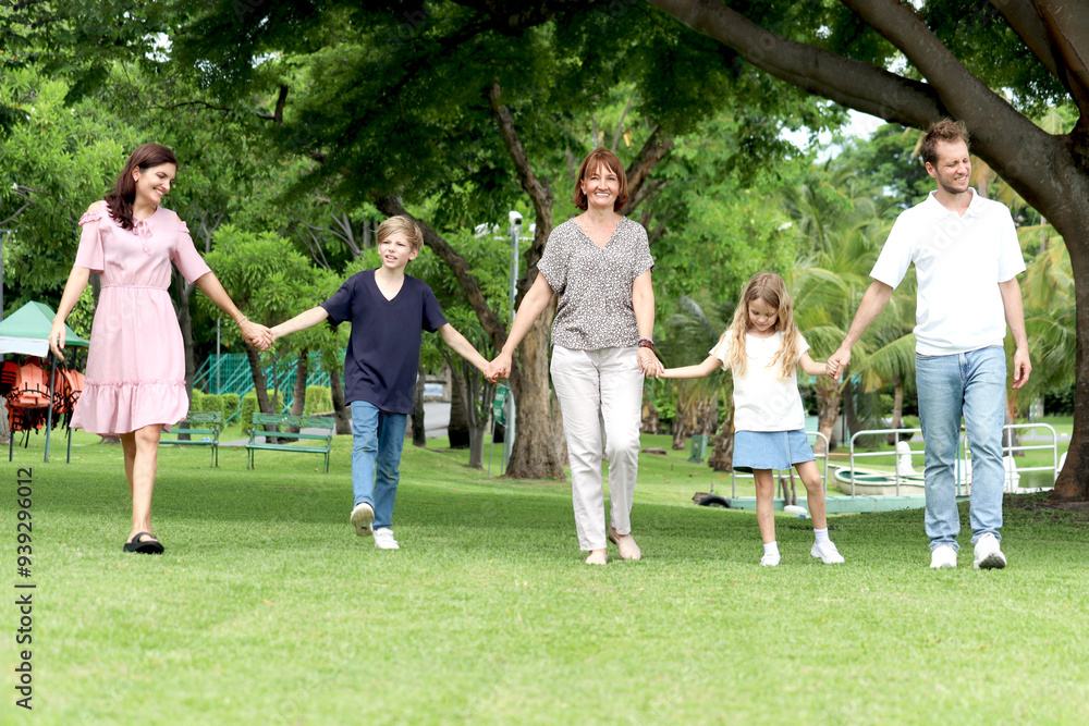 Happy cheerful family hold hands, walk in line together outside. Father, mother, daughter girl, son boy and elderly grandma take a walk in summer garden. Joyful kid, parents and senior at green park. Happy cheerful family hold hands, walk in line together outside. Father, mother, daughter girl, son boy and elderly grandma take a walk in summer garden. Joyful kid, parents and senior at green park.