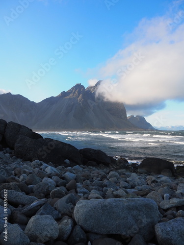 Foto Rocky shoreline with waves crashing against the rocks under a cloudy sky, embodying the power and unpredictability of nature captured in a seawater setting