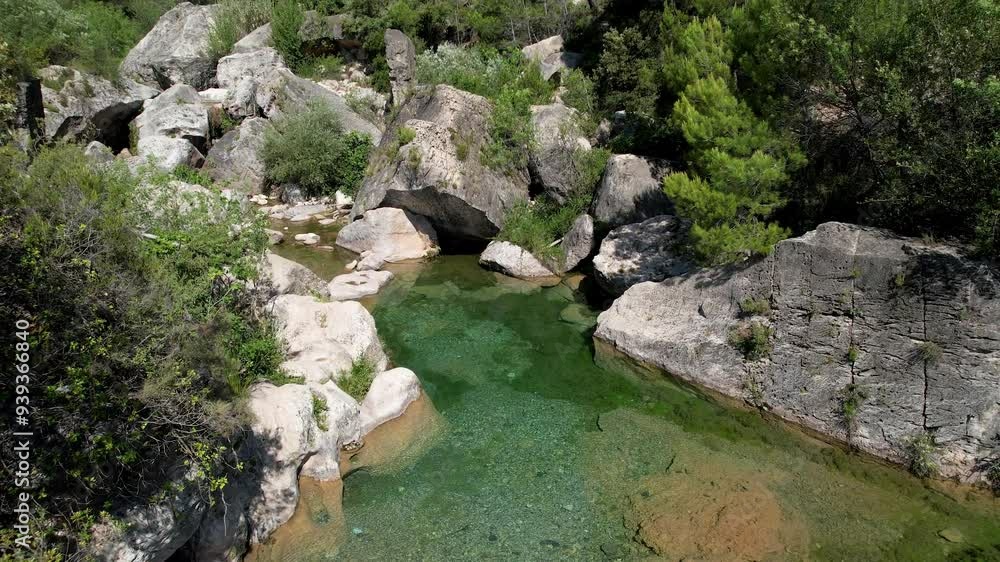 Tilt down aerial shot of small pool on the Brugent river on sunny summer day. La Riba, Tarragona Province, Spain. Tilt down aerial shot of small pool on the Brugent river on sunny summer day. La Riba, Tarragona Province, Spain.