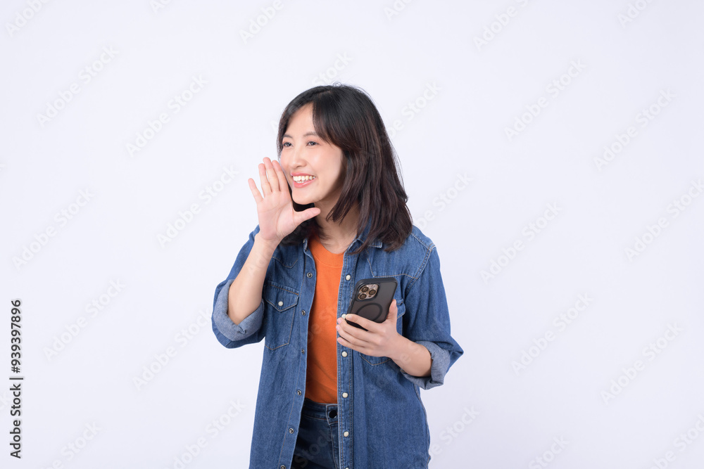 Cheerful woman smiling and waving while holding smartphone, expressing joy and friendliness. Cheerful woman smiling and waving while holding smartphone, expressing joy and friendliness.