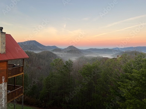 Morning mist rises over the Smoky Mountains with a cabin overlooking the serene landscape at dawn