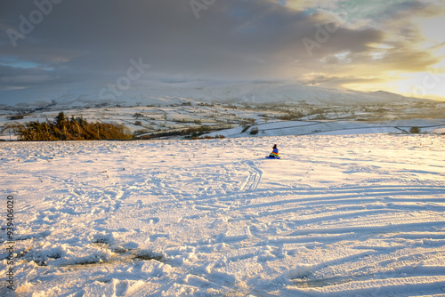 A child sleds in the snow during winter in the hills photo