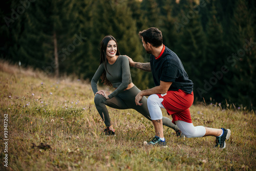 Smiling couple stretching after exercise outdoors in a green nature